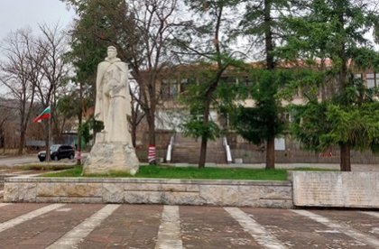 Typický motiv na návsi socialistické obce. Socha válečného hrdiny, v pozadí bulharská vlajka a budova Národního výboru (dnes obe