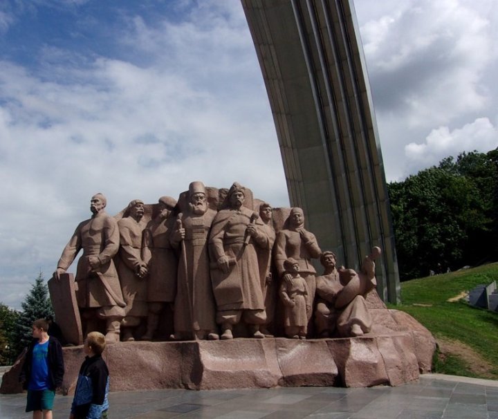 Socha u památníku přátelství národů. Vzadu ční oblouk. 