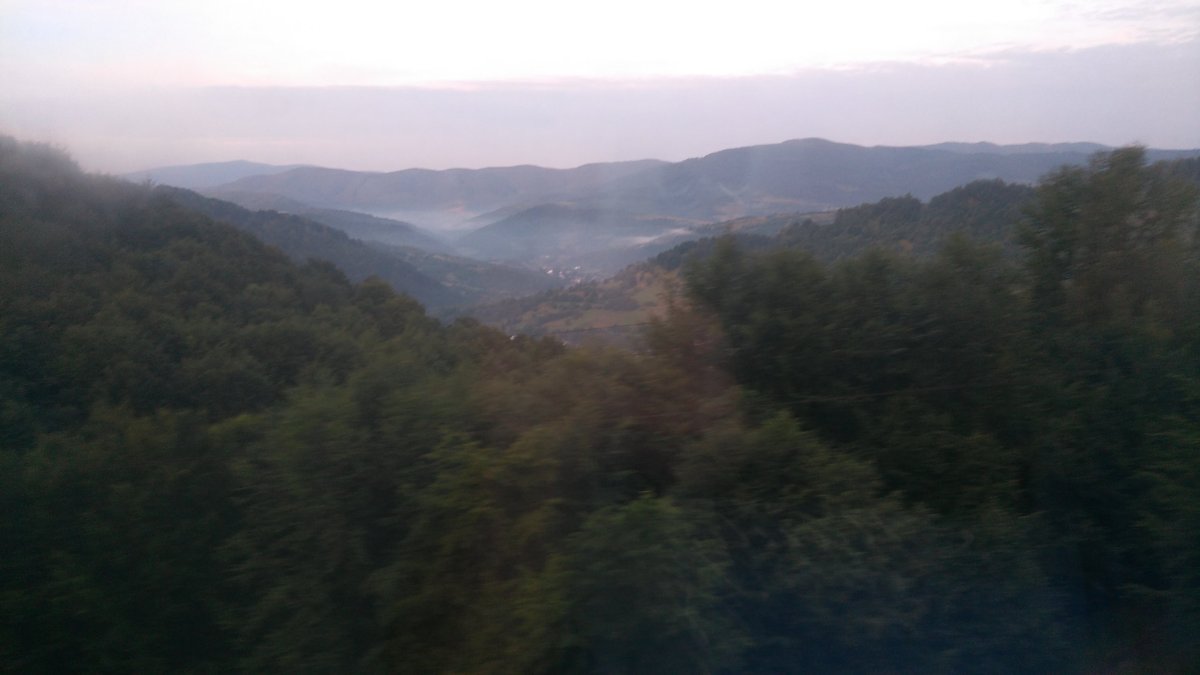 Pohled ze hřebene v Užockém průsmyku. Pára stoupá po ránu z lesů. Tam dolů v dáli pak sjedeme, trať tam vede údolím Uhu.