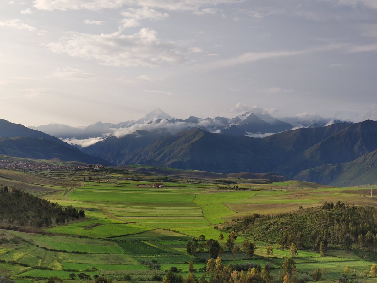 Zemědělská krajina v popředí, kaňon řeky Urubamby uprostřed a andské štíty v pozadí