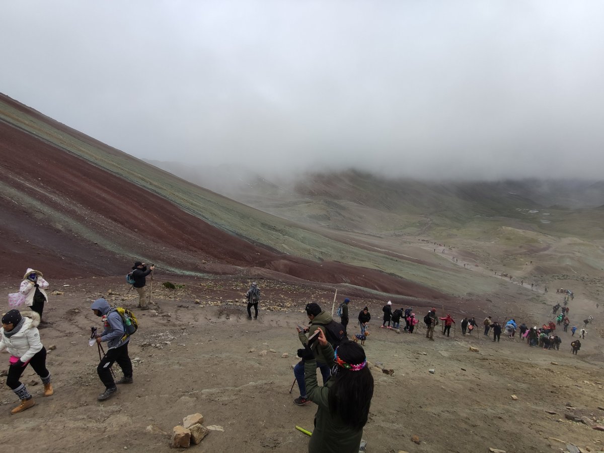 Zástupy lidí šplhajících do sedla k Rainbow Mountain