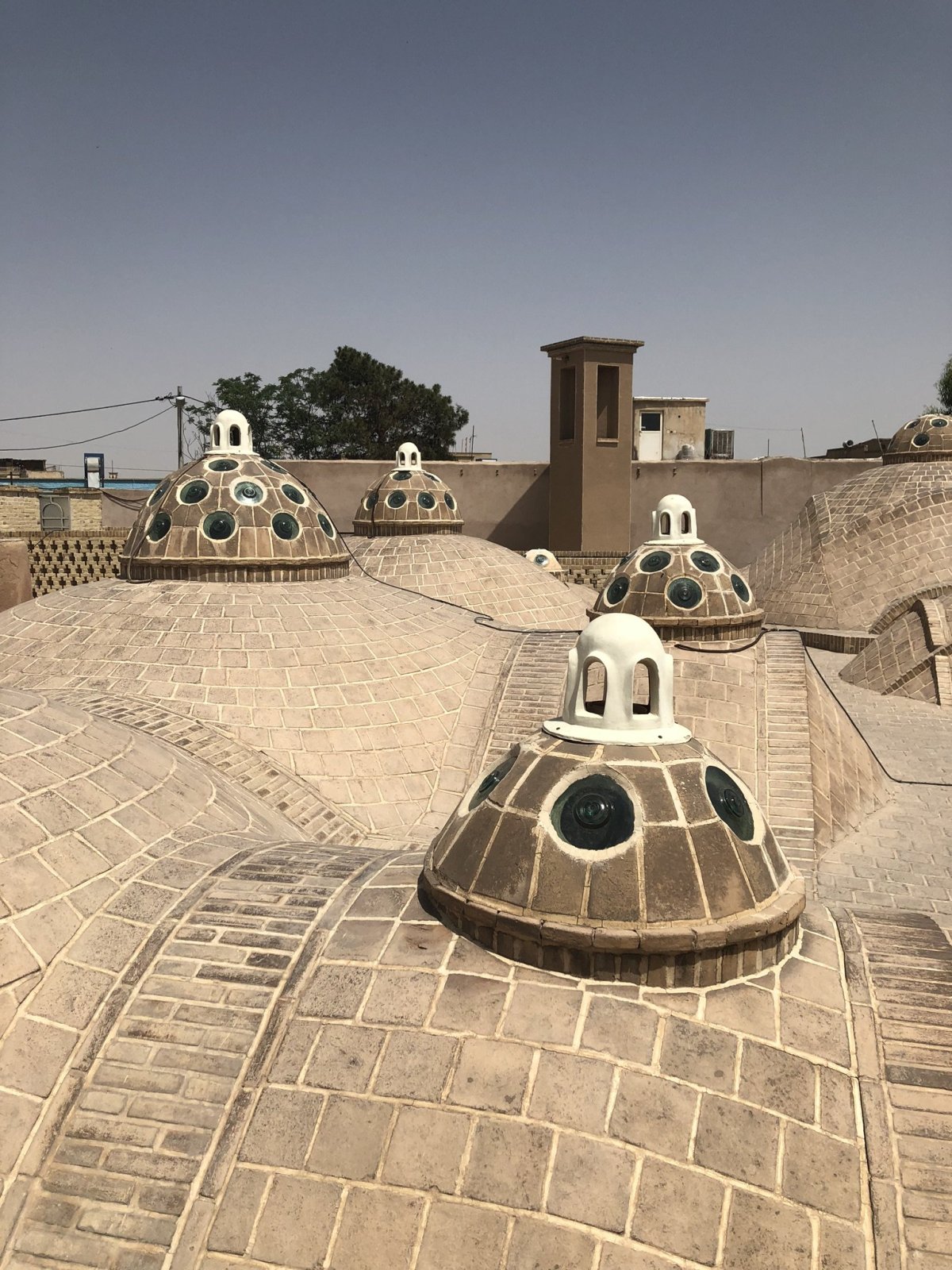 Střecha lázní s kupolemi pro odvod horkého vzduchu. A ten hranatý komín vzadu? Takhle vypadá ta stará íránská klimatizace.