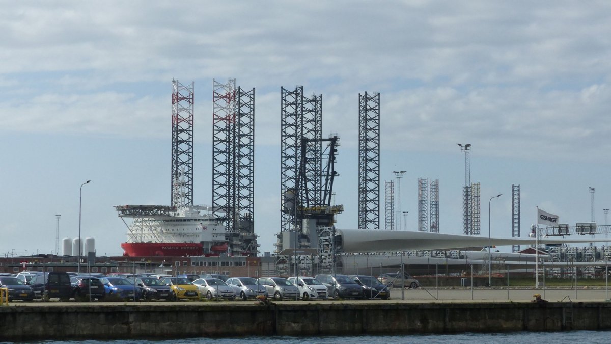 V pozadí stavba ropných plošin, v popředí větrných elektráren