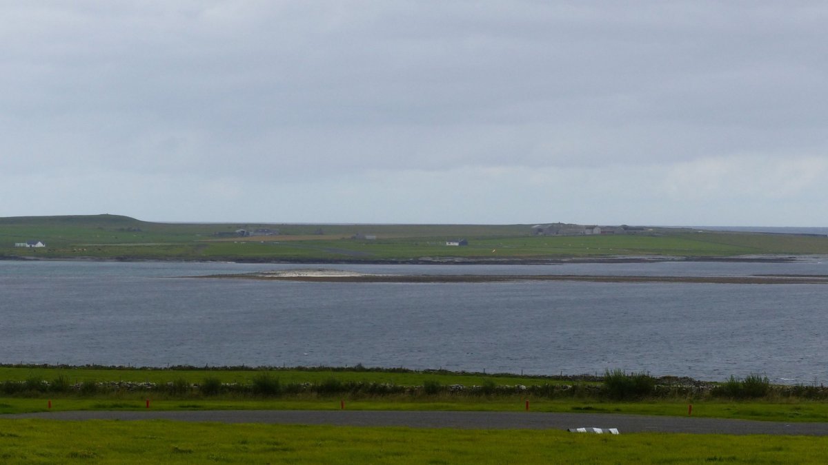 Pohled z druhé strany. V popředí runway na Papa Westray, v pozadí patrná dráha letiště Westray
